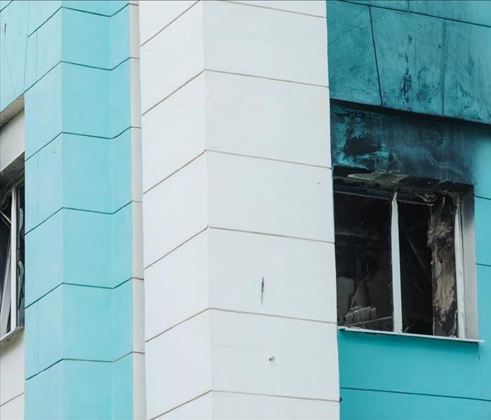 Window broken of a building, sky blue with white building, broken window with smoke damage