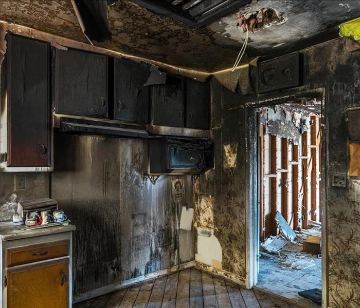 A kitchen with severe fire and soot damage.