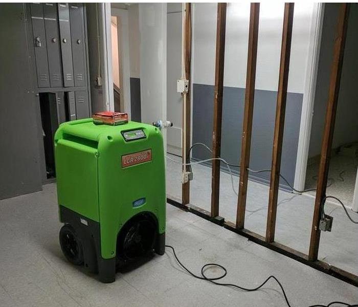 A dehumidifying machine of a restoration company is dehumidifying a business